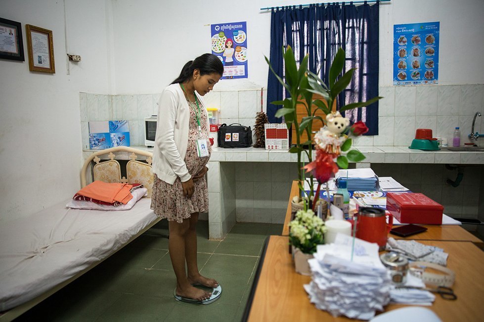 Maly, 25, checks her weight progress at 8-months pregnant during a visit to the factory’s infirmary. Phnom Penh, Cambodia. Mar. 14, 2018. © CARE / Erika Piñeros