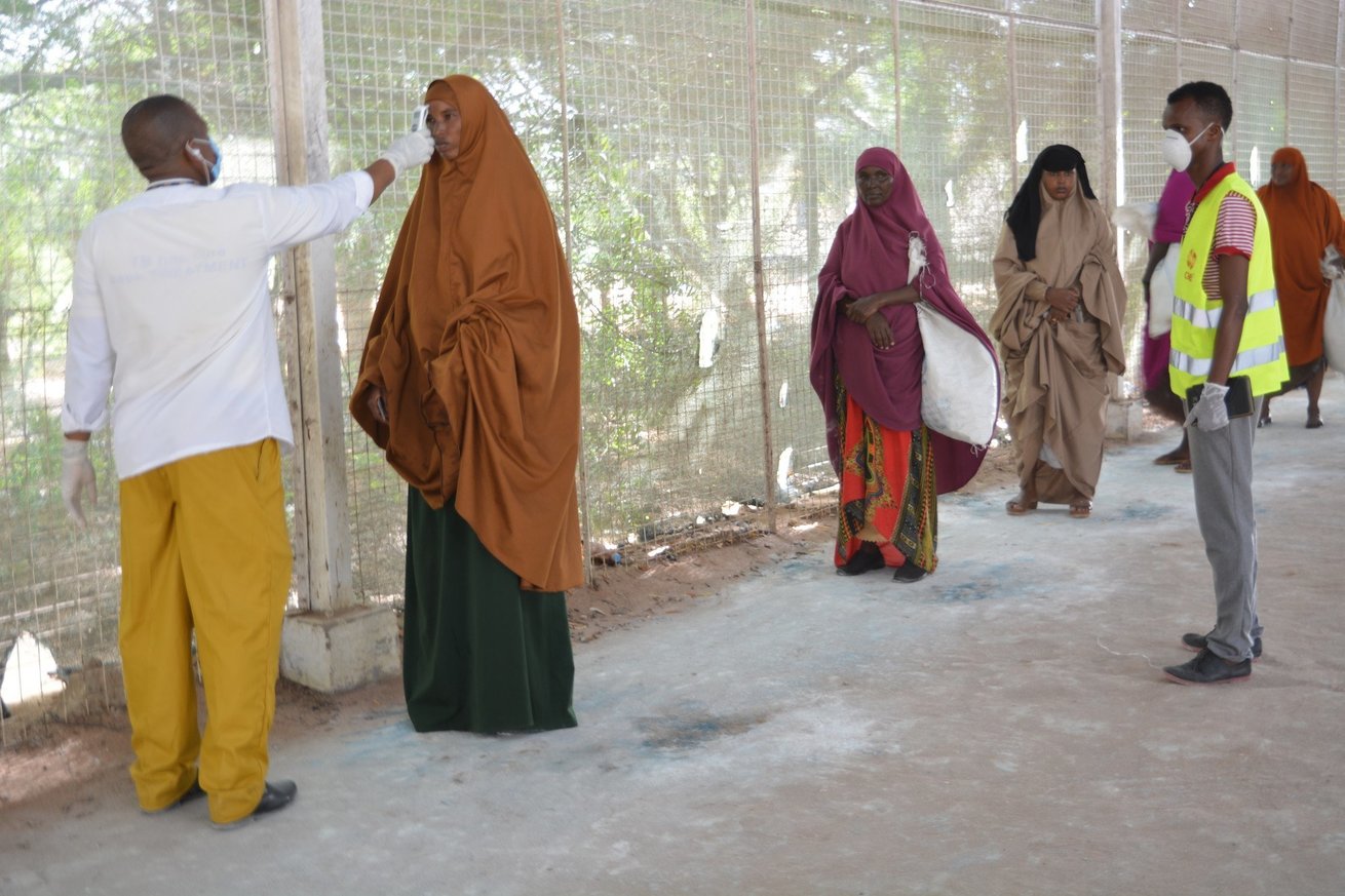 Women line up to have their temperature checked while maintaining social distance in Kenya’s Dadaab refugee complex 