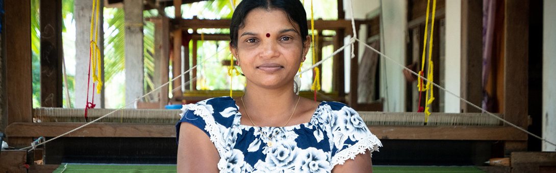 <p style="margin-left:0cm;margin-right:0cm"><span style="font-size:11pt"><strong>Kirupalini Karunakaran, Weaver, Sri Lanka</strong></span></p>  <p style="margin-left:0cm;margin-right:0cm"><span style="font-size:11pt"><strong><em>&ldquo;I am father and mother to my son and now, thanks to my business, I can buy him what he needs.&rdquo;</em></strong><em>&nbsp; </em></span></p>  <p style="margin-left:0cm;margin-right:0cm"><span style="font-size:11pt">Kirupalini, 32, runs her own weaving business selling beautiful handwoven garments to markets in the capital of Colombo over 300km away, as well as to buyers in other regions. </span></p>  <p style="margin-left:0cm;margin-right:0cm"><span style="font-size:11pt">But behind her smile and this strong looking woman, there is a different story of daily struggle and a past clouded by growing up during Sri Lanka&rsquo;s 30-year civil war.&nbsp; Aged 19, she was hit by shrapnel from a bomb blast and has a visible welt in her arm as a daily reminder.&nbsp; Towards the end of the war there was major displacement within the country and Kiurpalini, her parents and her seven siblings had to quickly leave the safety of their own home, before it was razed to the ground.&nbsp; She adds: &ldquo;I can&rsquo;t count the number of places we moved to, sometimes it was two days here, a week there, but eventually we ended up in Menik Farm camp for six months.&rdquo;</span></p>  <p style="margin-left:0cm;margin-right:0cm"><span style="font-size:11pt">It was at this camp where she married her school friend and she quickly fell pregnant.&nbsp; Sadly, he left her when she was only three months pregnant. Her son, now aged eight, has a brain injury and attends a special needs school.&nbsp;&nbsp; She glows with pride when she speaks about her son and pulls out her phone to show pictures, adding: &ldquo;I am father and mother to my son and now, thanks to my business, I can buy him what he needs.&rdquo;&nbsp; She has also become President of the Spe