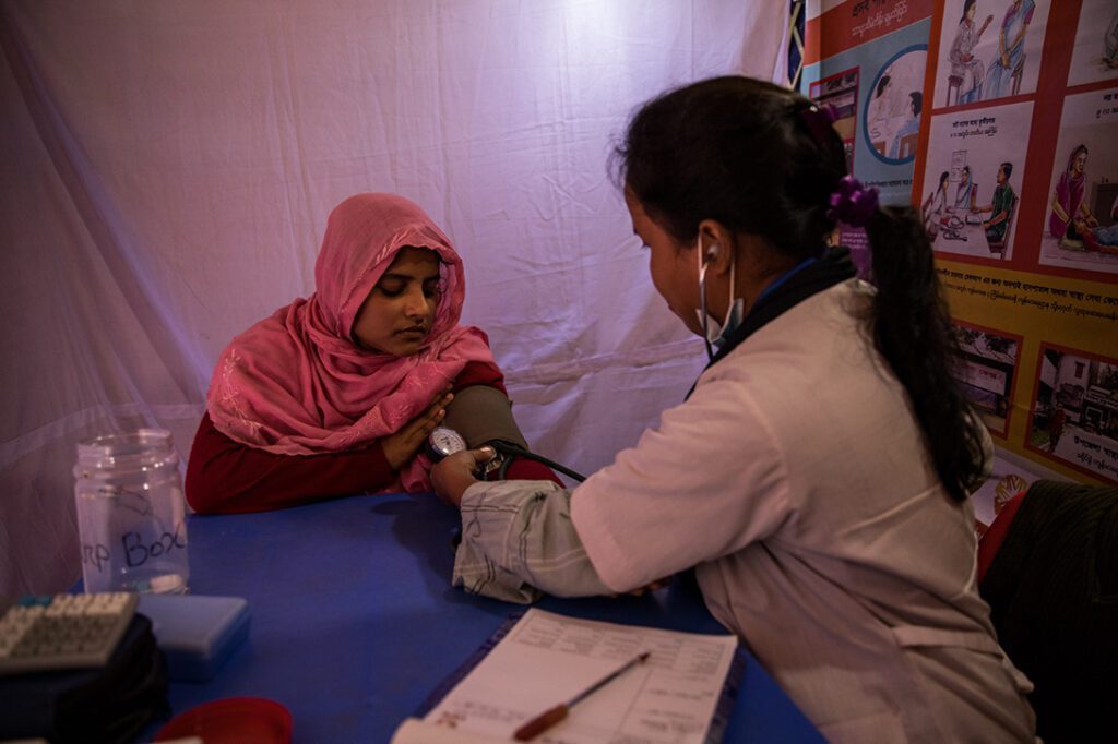 A Rohingya woman being diagnosed by a CARE Bangladesh health worker at a mobile health clinic in Bangladesh.
