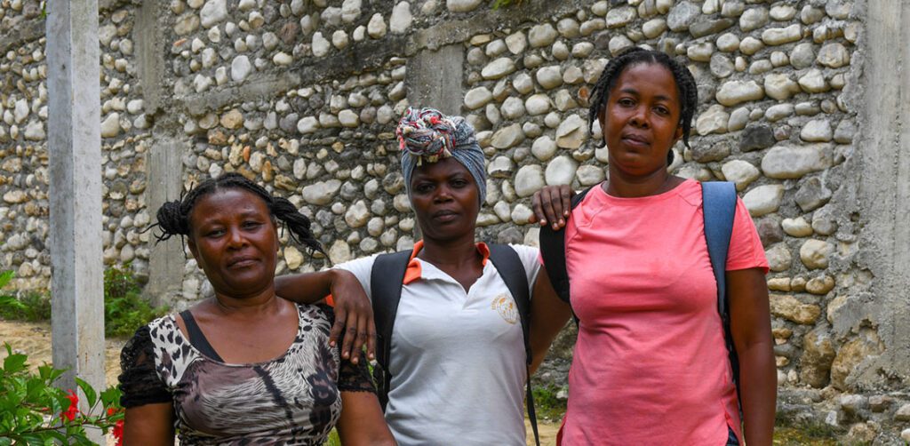 Pamphile Fabiana, a CARE village agent who lives in the town of Latibolière, in the 4th section of Basse Guinaudé, speaks about what she and her community lost in the August 2021 7.2 magnitude earthquake that caused massive loss of life and property in southern Haiti. Fabiana (in pink shirt) is pictured w other members (names not known) of her community near a damaged school in late August 2021. "We have lost all our possessions, such as: our houses, our churches, our schools, our health centers, all our animals, some members of our families are victims, their feet are broken," She said (using Google translate).