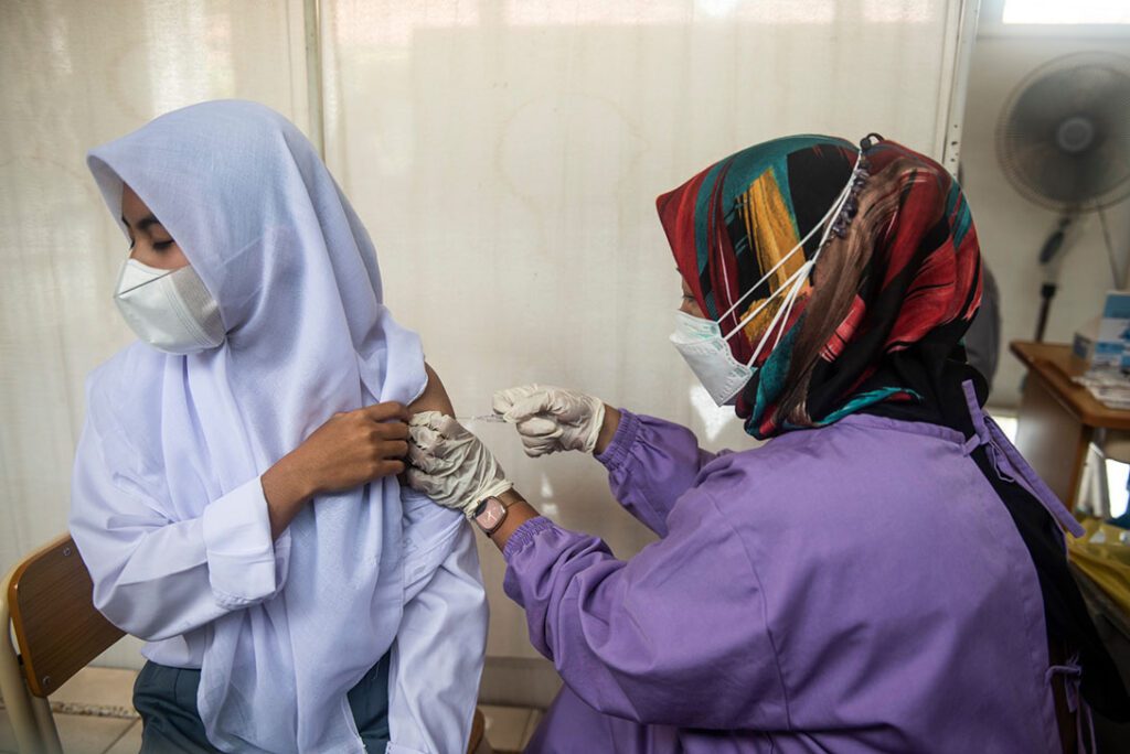 A health worker injects the vaccine to students during vaccine program in Cinangka Public High School, Serang, Banten, Indonesia in August 2021.Rosa Panggabean/CARE