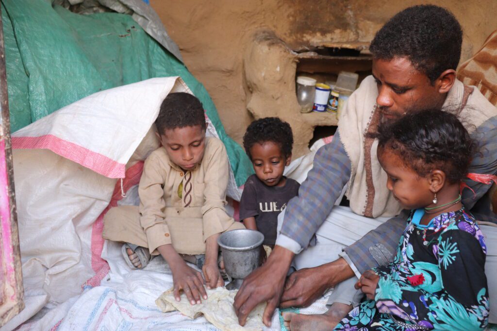 A family in Yemen sits together preparing a meal. Most family members only eat once each day. Khalid Al-Ashmori/CARE