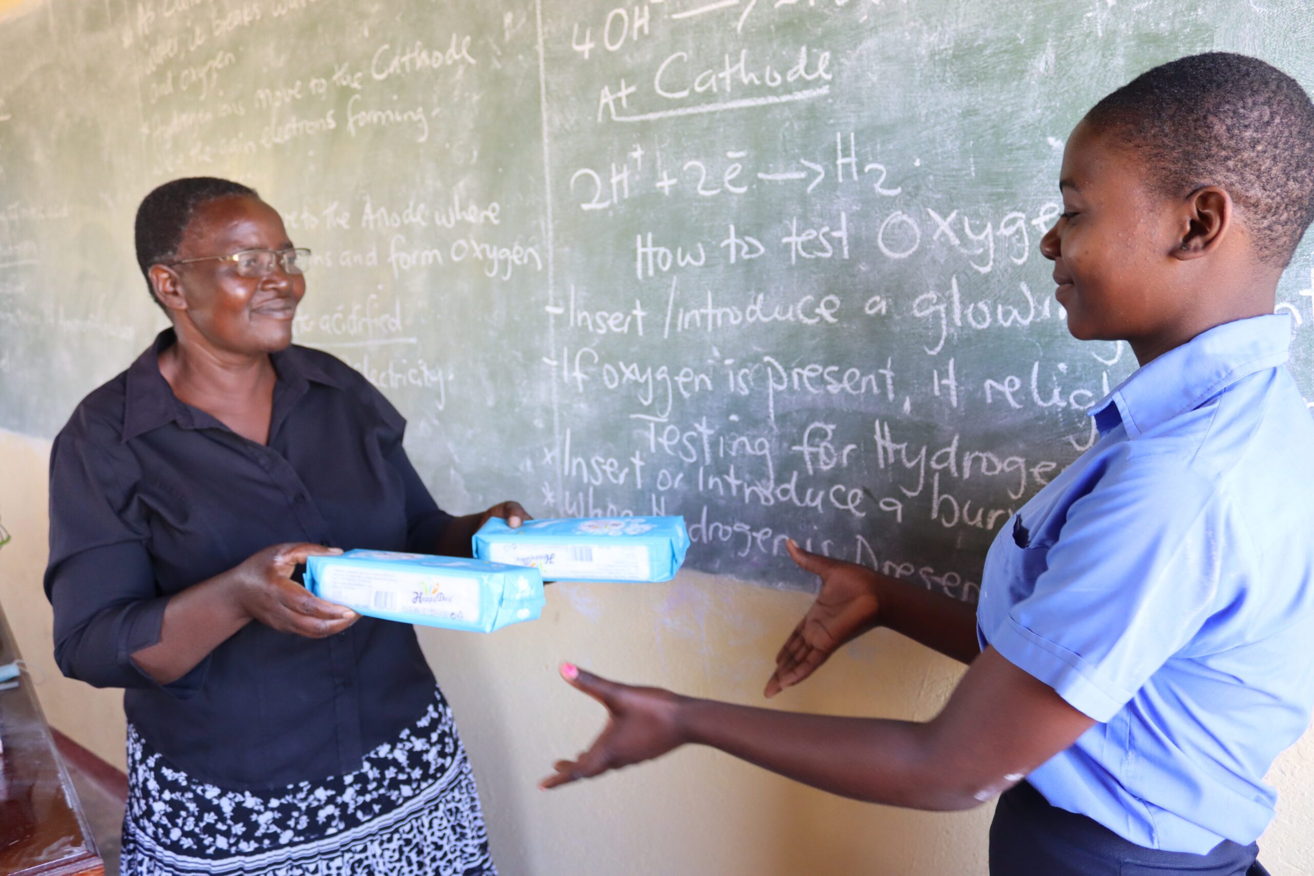 Middle aged woman giving health kits to a girl in school