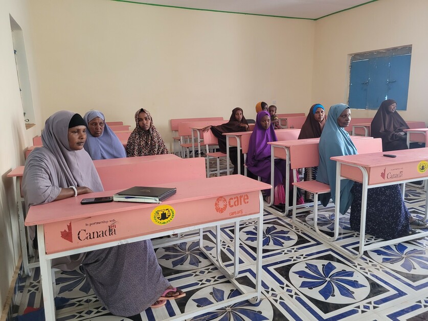 Girls sit facing forward at desks in a classroom