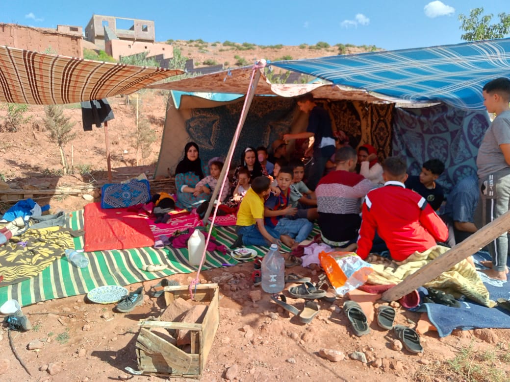 Several people huddle together under a makeshift shelter after the earthquake in Morocco