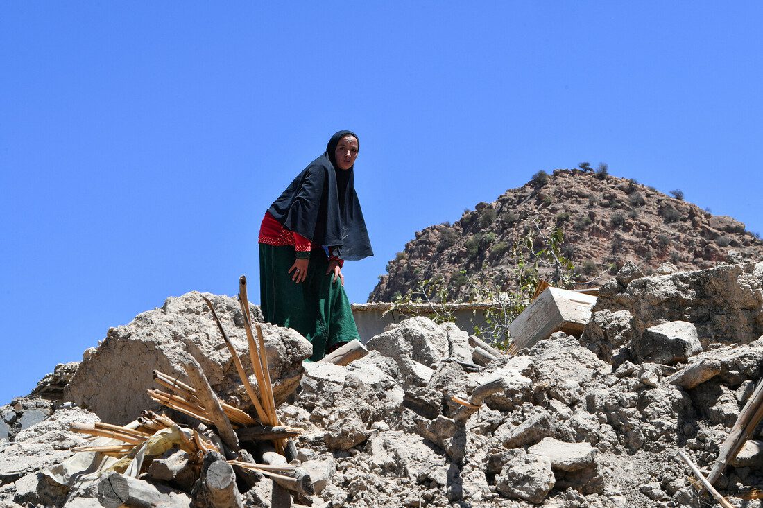 A woman stands on top of a pile of rubble.