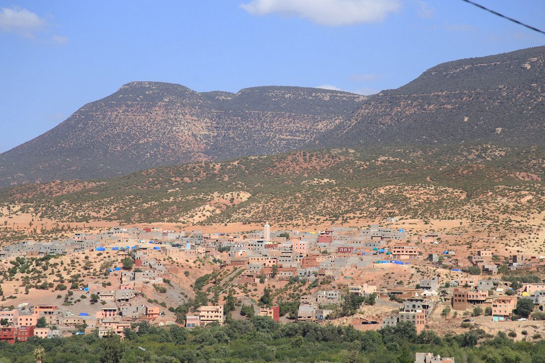 A Moroccan landscape with houses and mountains in the distance.