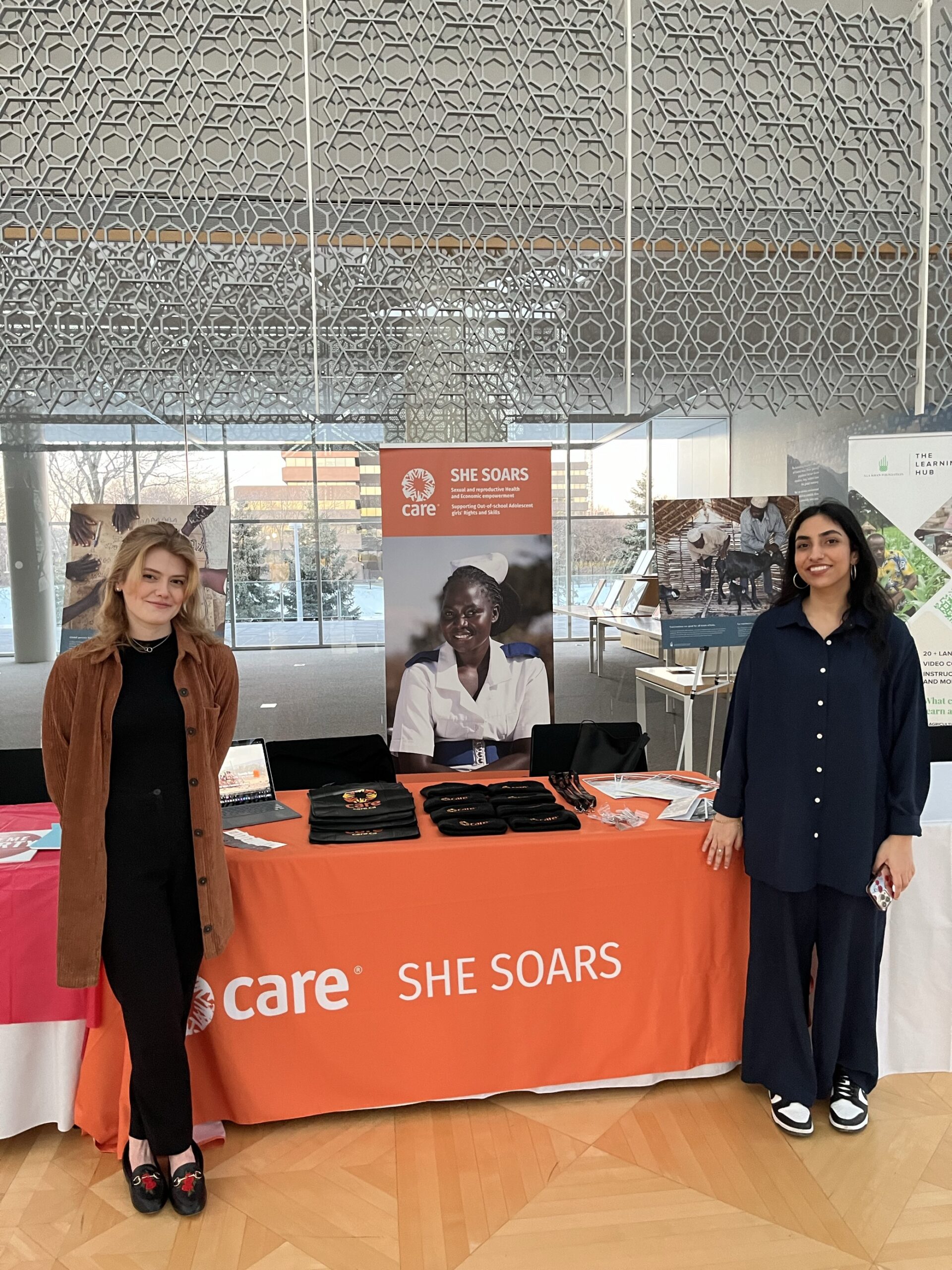 2 women standing at a CARE SHE SOARS booth at an event.