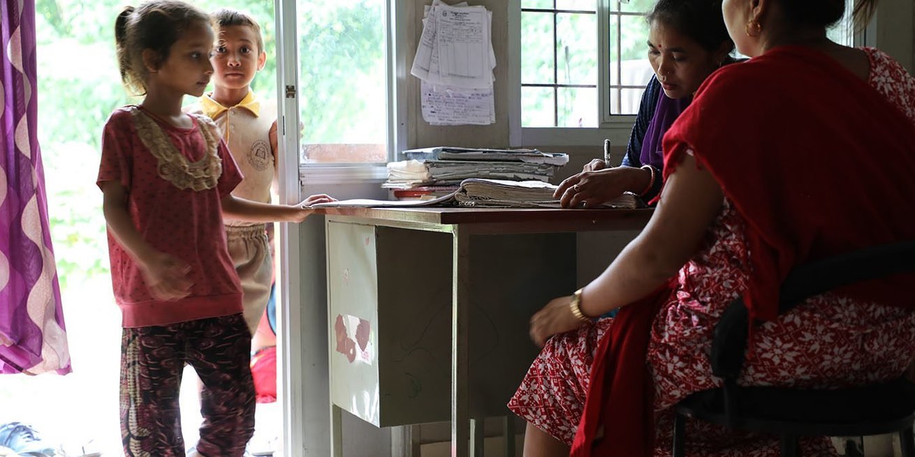 CARE-trained birth attendant Muna Bayalkoti, in purple, receives patients at a health clinic in Gankhu village. CARE helped establish this facility after the earthquakes of 2015 and now the community sees zero home births.