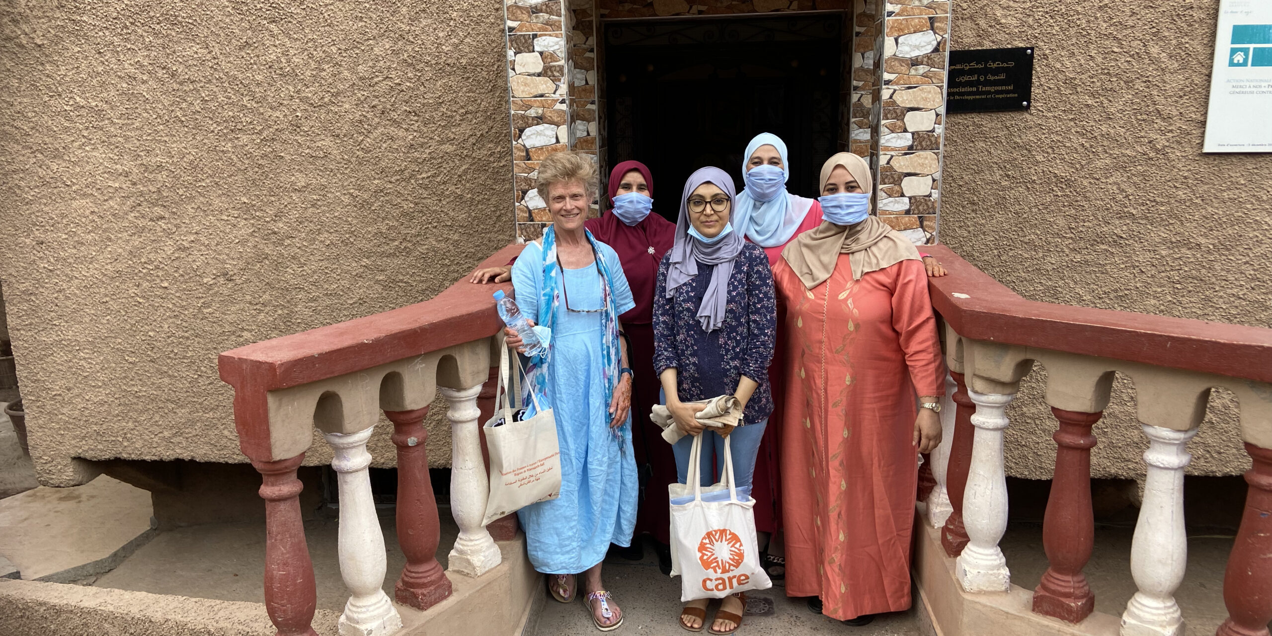 A group of five women stand in an outside doorway. They are grouped together for the photo.
