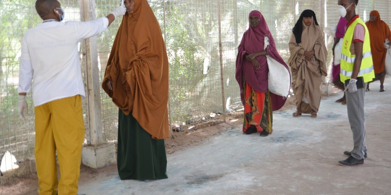 Women line up to have their temperature checked while maintaining social distance in Kenya’s Dadaab refugee complex