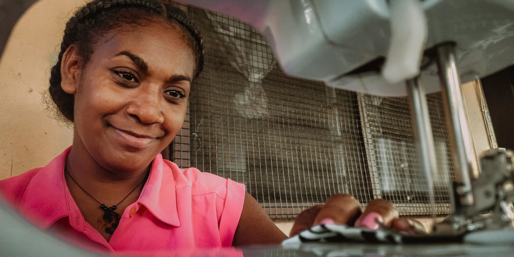 Regina smiling as she sits at her sewing machine. Valerie Fernandez/CARE